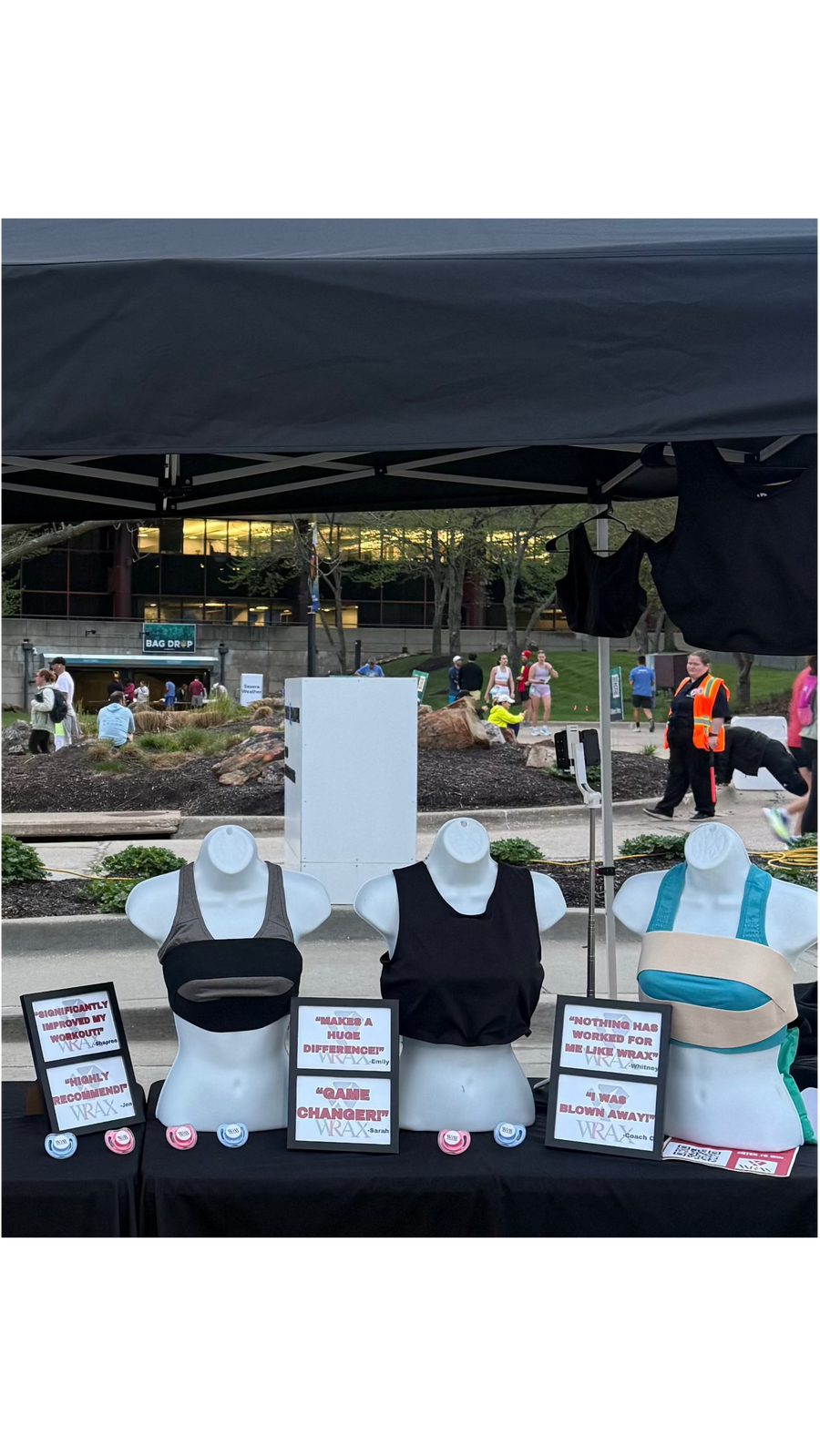 The WRAX booth set up outdoors under a black canopy, with product displayed on forms along a draped table